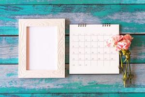 Carnation flower on blank picture frame and calendar on wood background, Valentine's Day, Mother's Day or Birthday background photo