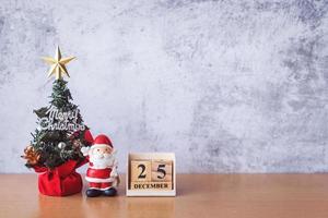 Block calendar date December 25 calendar and Christmas decoration - Santa Clause, tree and gift on wooden table. Christmas and Happy new year concept photo