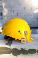 Construction yellow hardhat and key to house on window of housing made of blocks of porous concrete. Turnkey construction, future home, engineering, building. Work safety. Copy space photo