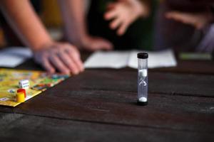 Board game board, chips, cube, timer on a dark wooden table and hands in the background. The concept of teamwork, intellectual relaxation, corporate event, playing at home with children. Copy space photo