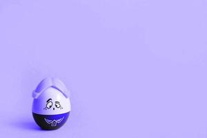 Funny egg toy with a man's sad face on a yellow background. Easter, solitude. Copy space photo