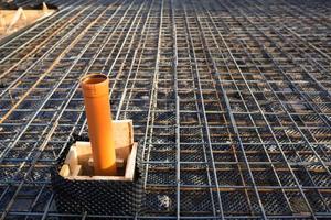 Iron fittings on a wooden formwork with laid pipes are the basis for pouring the foundation of the house with a concrete slab. Construction of cottages, design, engineering communications. photo