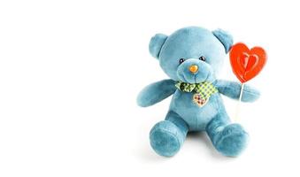 Turquoise soft teddy bear with red lollipop heart on a stick on a white background. Love, a gift to a girl, a declaration of love, Valentine's day. Copy space