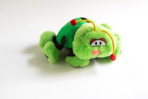 Soft plush toy for children - green ladybug. A beetle with sad eyes, red bells on its antennae, unrealistic color with black spots and large paws.Children's toy close-up, space for text photo