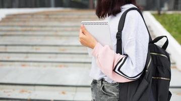 A female student with a black backpack and a notebook in her hands stands on the steps in front of the Institute. Higher education, the beginning of the school year, back to school. Copyspace photo