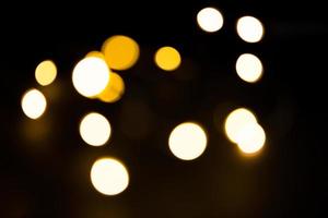 Yellow and gold lights garland in a blur on a black background. Bokeh of flying circles in the defocus. Festive atmosphere of Christmas and new year. Celebrate background photo