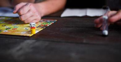 Kaluga, Russia - June 20, 2020. Board game Ekivoki, chips, cube, timer on a table and hands in background. Teamwork, intellectual relaxation, corporate event, playing at home with children. Copy space photo