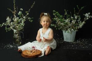 niña celebra su primer cumpleaños. niña comiendo su primer pastel. foto