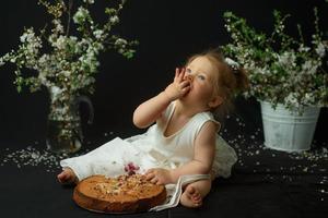 niña celebra su primer cumpleaños. niña comiendo su primer pastel. foto