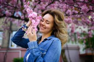 Spring Portrait. Beautiful Young Woman with Sakura. Outdoor photo