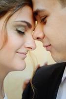 An attractive and stylish man with a short beard on his face kisses a beautiful girl in the nose with dark hair and a sweet smile. Wedding of two lovers of people. focus on the girl's man is blurred. photo