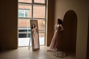 Young girl in dress inside room sits window photo