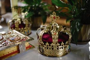 corona dorada con piedras preciosas en una servilleta roja en el altar de la iglesia. ceremonia de boda tradicional, religión foto