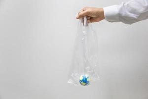 Save Global Environment Care Concept. Close up of businessman hand holding plastic bag with mini world ball inside with copy space. photo