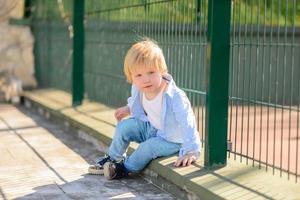 Little blond boy runs on the background of a tennis court photo