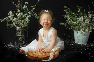 Little girl celebrates her first birthday. Girl eating her first cake. photo