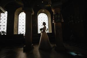 silueta de una novia en una iglesia contra el fondo de una vidriera.