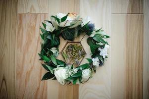close up view of white flowers, wedding rings in rustic box with plants inside photo