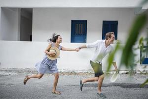 Young couple fooling around but against a white building photo