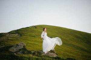 mujer con vestido de novia corre por el campo hacia las montañas