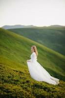 mujer con vestido de novia corre por el campo hacia las montañas foto