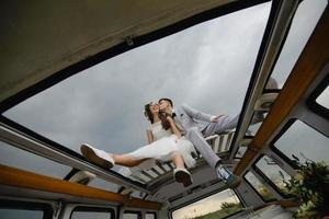 Hipster bride and groom are standing near their retro bus. photo