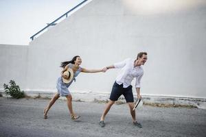 Young couple fooling around but against a white building photo