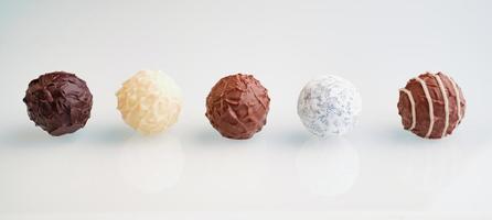 row of five chocolate truffles on white background photo