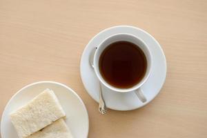 Top view of a cup of hot tea with sandwich on wooden table photo