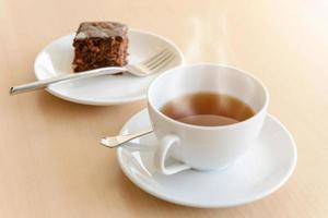 cup of hot tea with brownie on wooden table photo