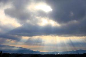 un rayo de hermosa luz solar brilla a través de la nube sobre la montaña foto