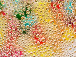 Abstract colorful vivid background with large and small spherical convex drops of water on the glass. Macro, top view, close up. photo