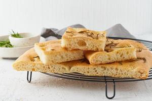 Focaccia, pizza, italian flat bread with rosemary and olive oil on grid photo