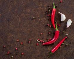red hot chili pepper pods and peas, garlic clove on dark rusty metal background, top view, copy space photo