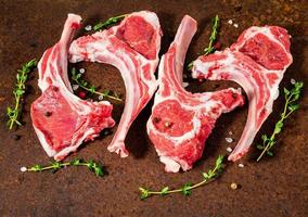 raw lamb cutlets on bone on dark metallic background, side view, close up photo