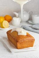Lemon bread coated with sugar sweet icing. Whole loaf. White background, side view, copy space