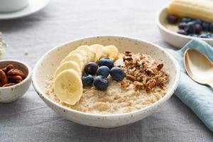 Whole oatmeal, large bowl of porridge with banana, blueberries, nuts for breakfast, photo