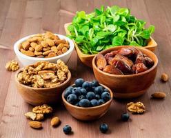 Healthy vegan food - dry fruits, greens, nuts, berry. Superfoods on brown wooden background, side view photo
