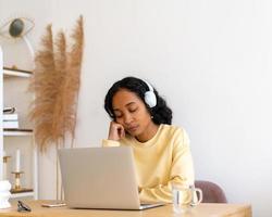 estudiante afroamericana aburrida durmiendo durante las clases en línea en una laptop en casa foto