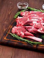 Raw lamb cutlets on bone on dark brown wooden background, lamb ribs, side view, vertical photo