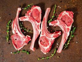 raw lamb cutlets on bone on dark metallic background, top view, close up photo