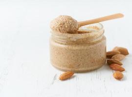 Almond butter, raw food paste made from grinding almonds, glass jar, side view, close up photo