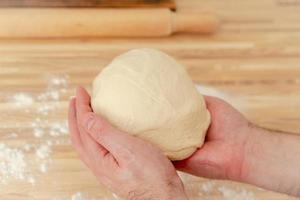 Faceless man kneading dough on kitchen table at home, apartment, flour, scales photo