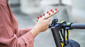 primer plano de la mujer de la mano sosteniendo las manos del teléfono inteligente y usando la aplicación de mapas antes de viajar en scooter eléctrico en la ciudad foto