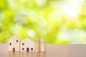 Wood doll couple lover stand in near house model with green bokeh as background, self-quarantine and stay safe at home concept for Coronavirus, 2019-NCOV or COVID 19 prevention photo