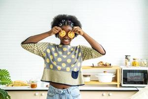 African american happy girl having fun with food vegetables at kitchen holds tomatoes before his eyes like in glasses, Teaching child to healthy and varied vegitarian food