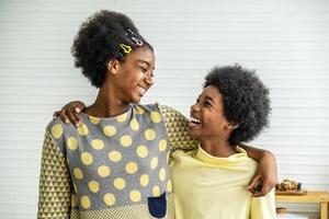 Happy Kids.Two cute adorable siblings african american children hug the neck and smile, Older sister hugs little brother by the neck photo