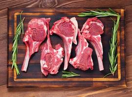 Raw lamb cutlets on bone on dark brown wooden background, lamb ribs, top view.