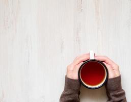 Female hands holding a mug of hot black tea. photo