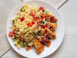 Turkey meat, fried, with teriyaki sauce and sesame seeds. Couscous with vegetables. Selective focus, day natural light photo